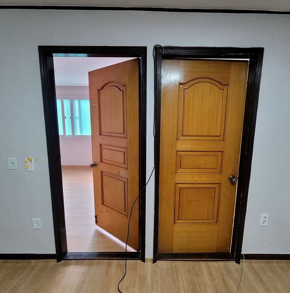 안성 방문교체 시공 전 — 짙은 색 구형 방문 두 짝이 낡아 있던 상태
